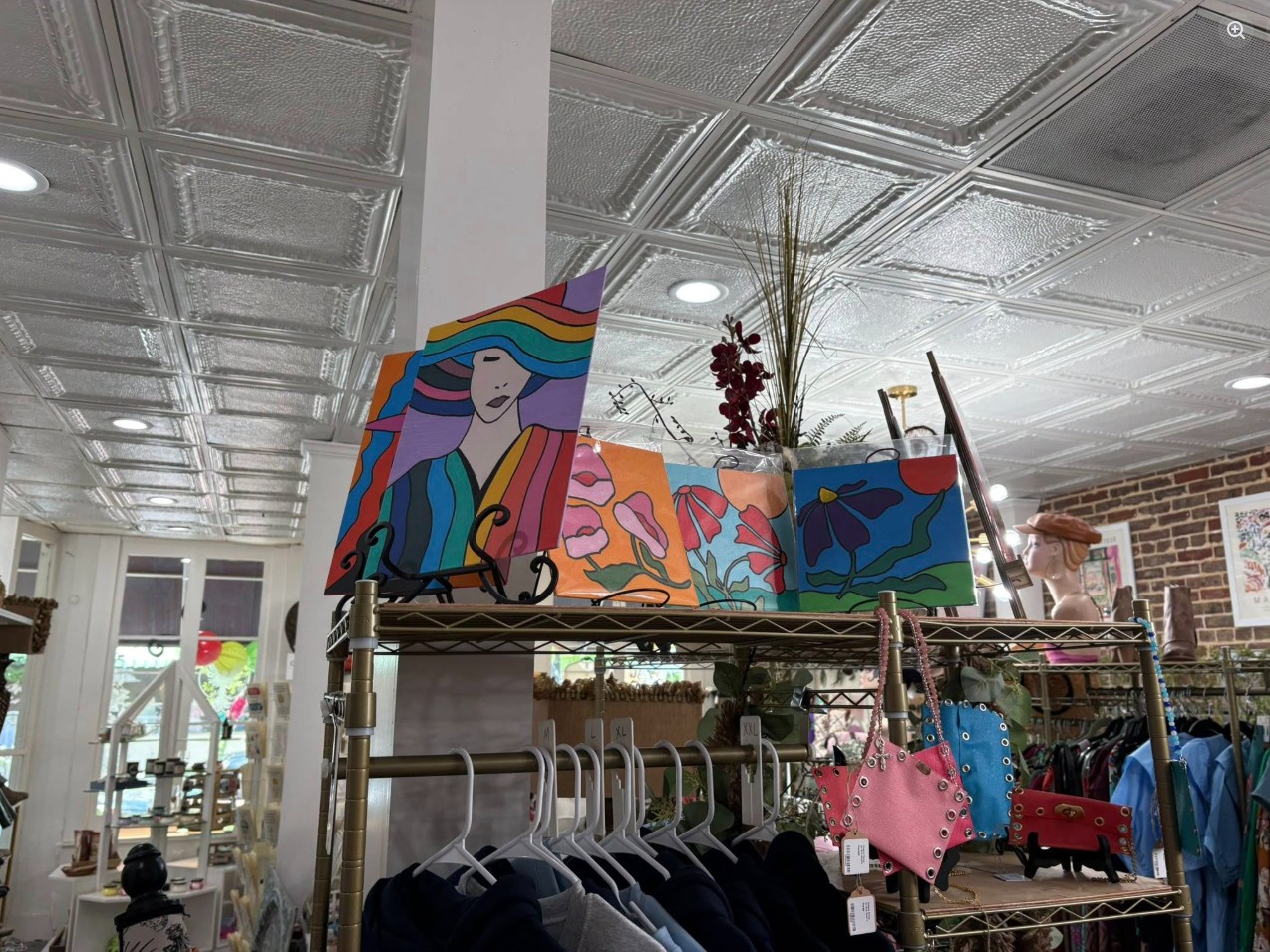 Colorful pop-art paintings displayed above clothing racks