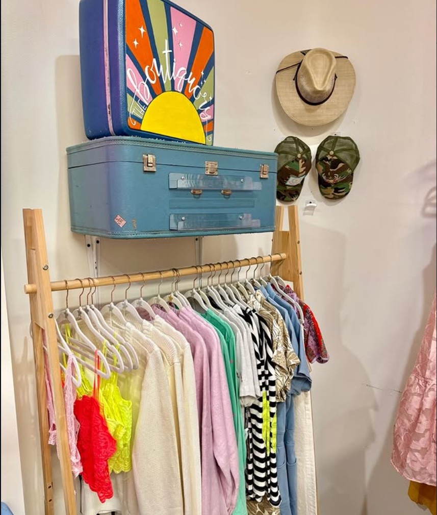 Colorful clothing rack with vintage suitcase display