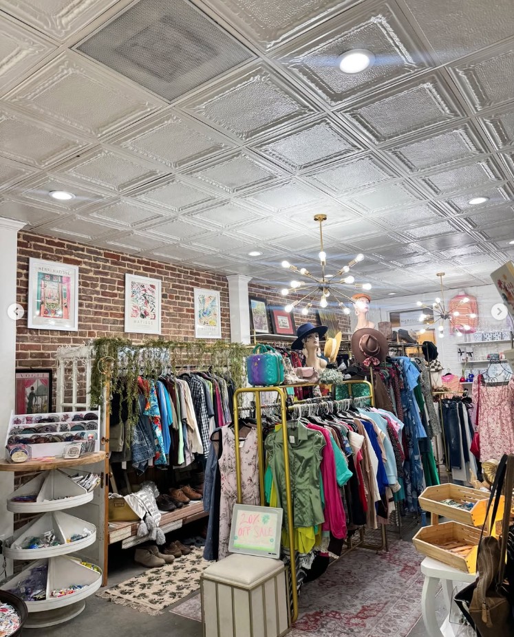 Inside Phoenix Rising — racks of clothes under tin ceiling